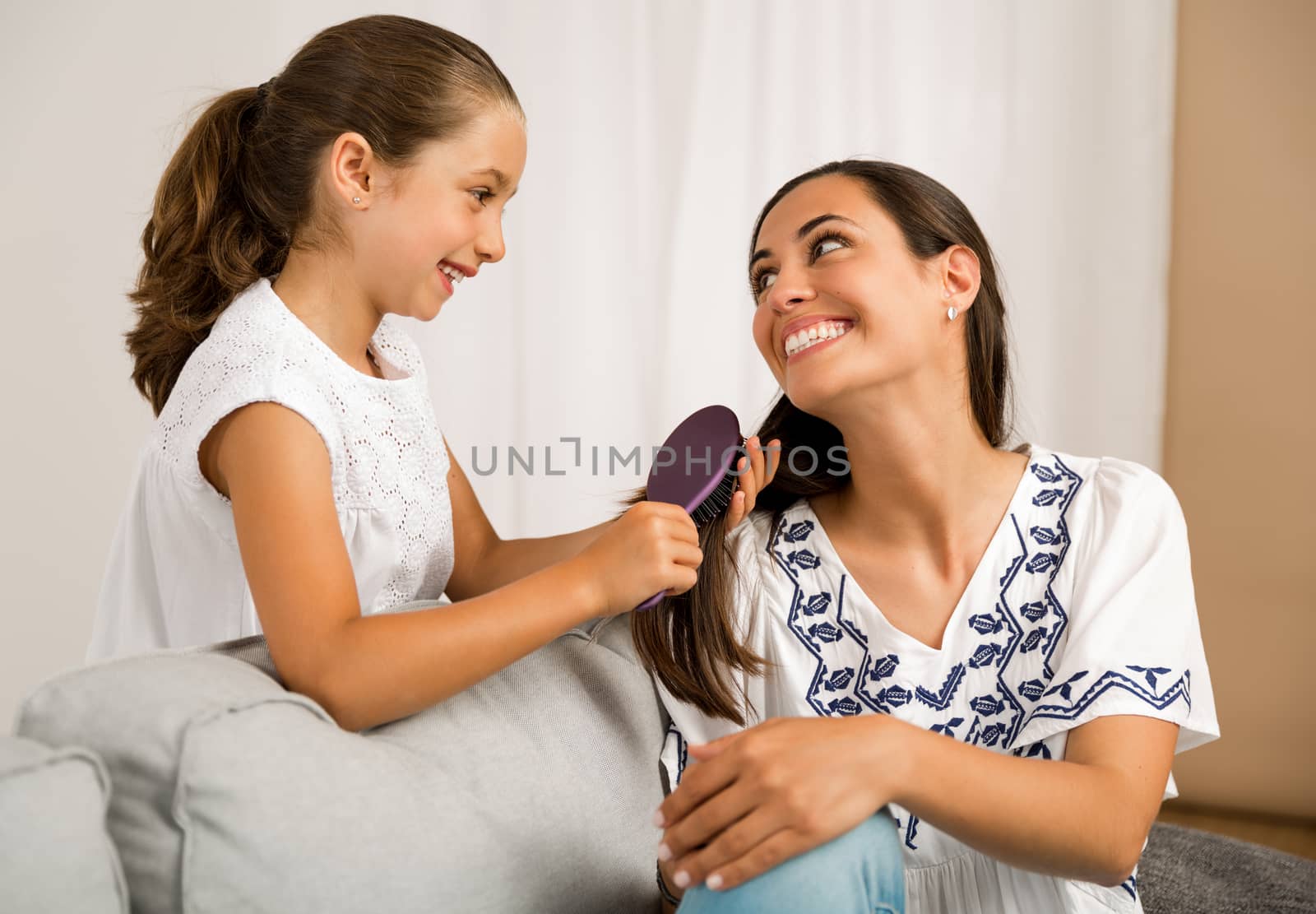 Litle girl helping mother brushing her hair