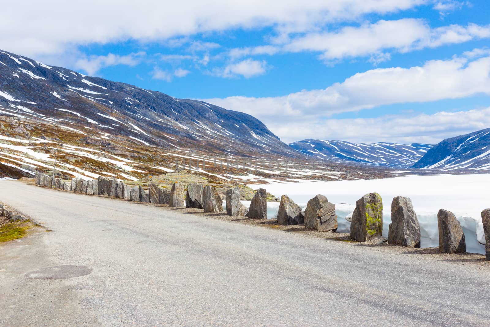Old road with stones in summer with snow in Norway mountains