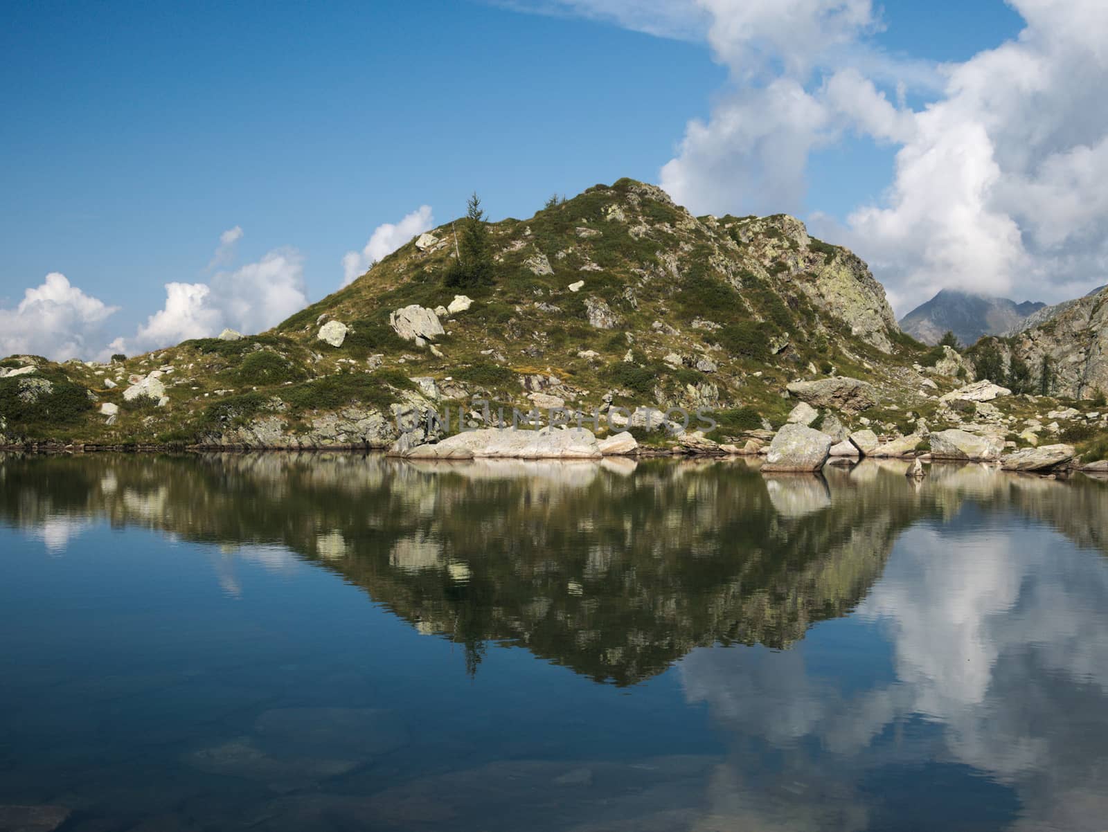 Mountains reflect on small alpine lake on the Bergamo Alps, northern Italy
