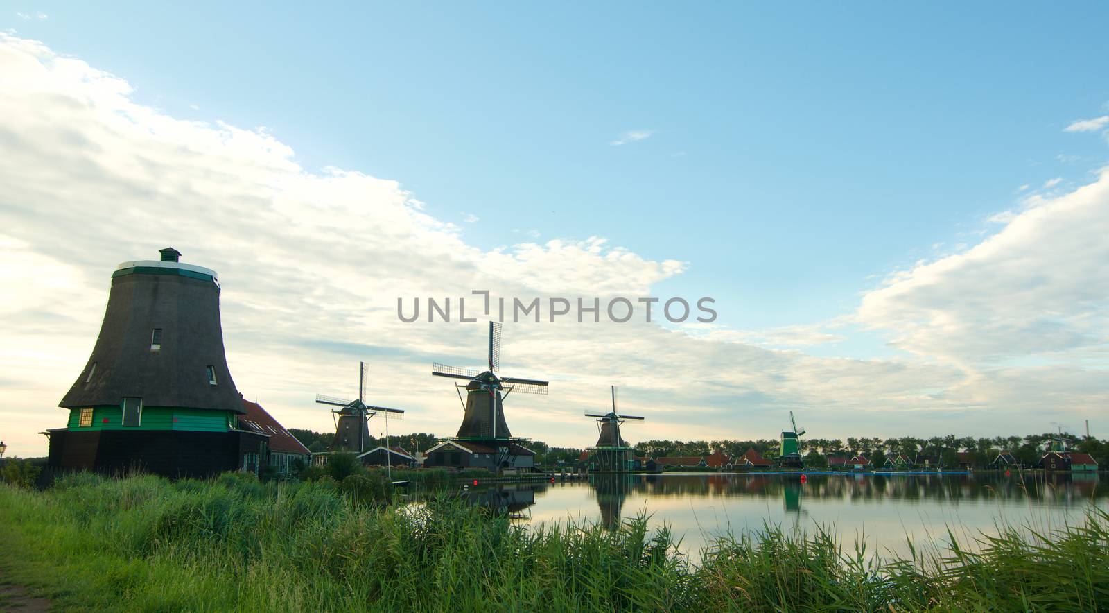 Famous Zaanse Schans Windmills from River Coast with Reflection on Water Early Morning Outdoors