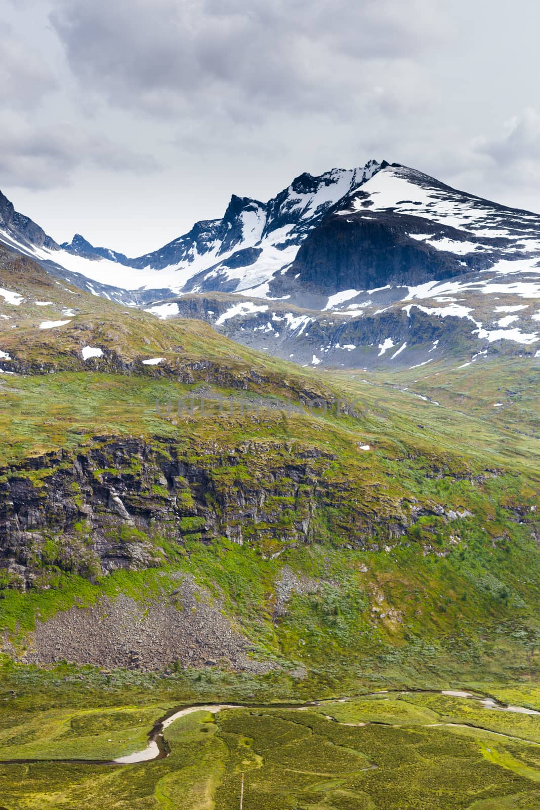 Mountain in snow and green river valley in Norway