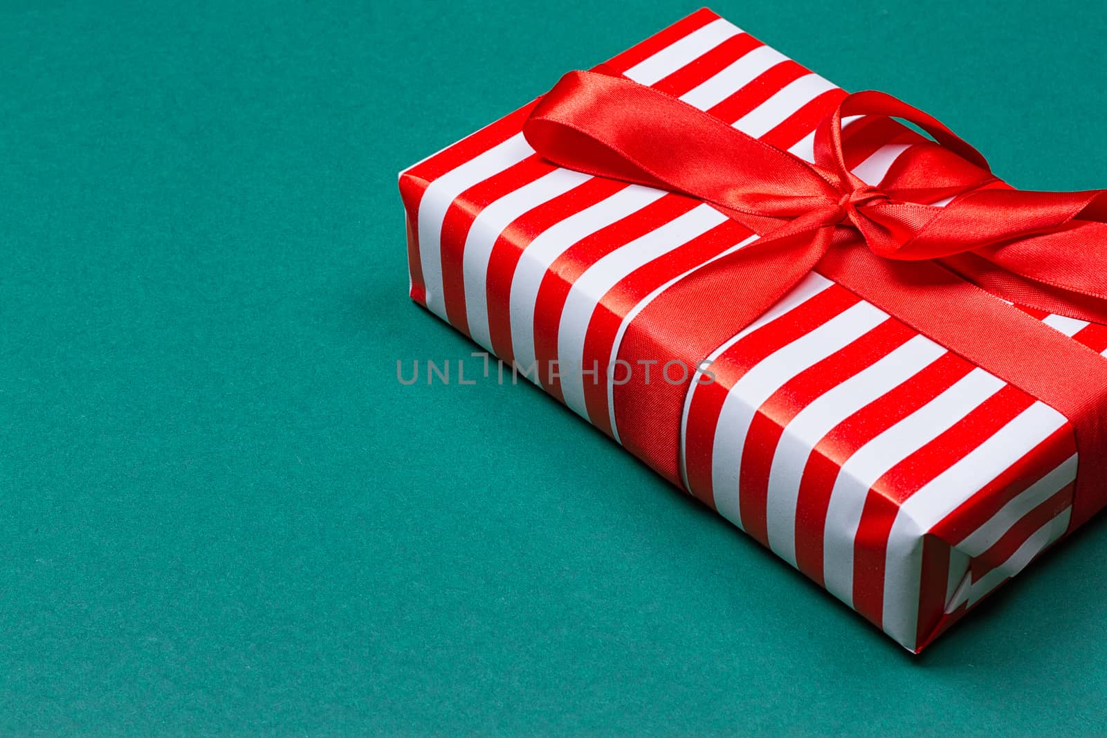 Gift box with ribbon on green background. Close up. Top view.