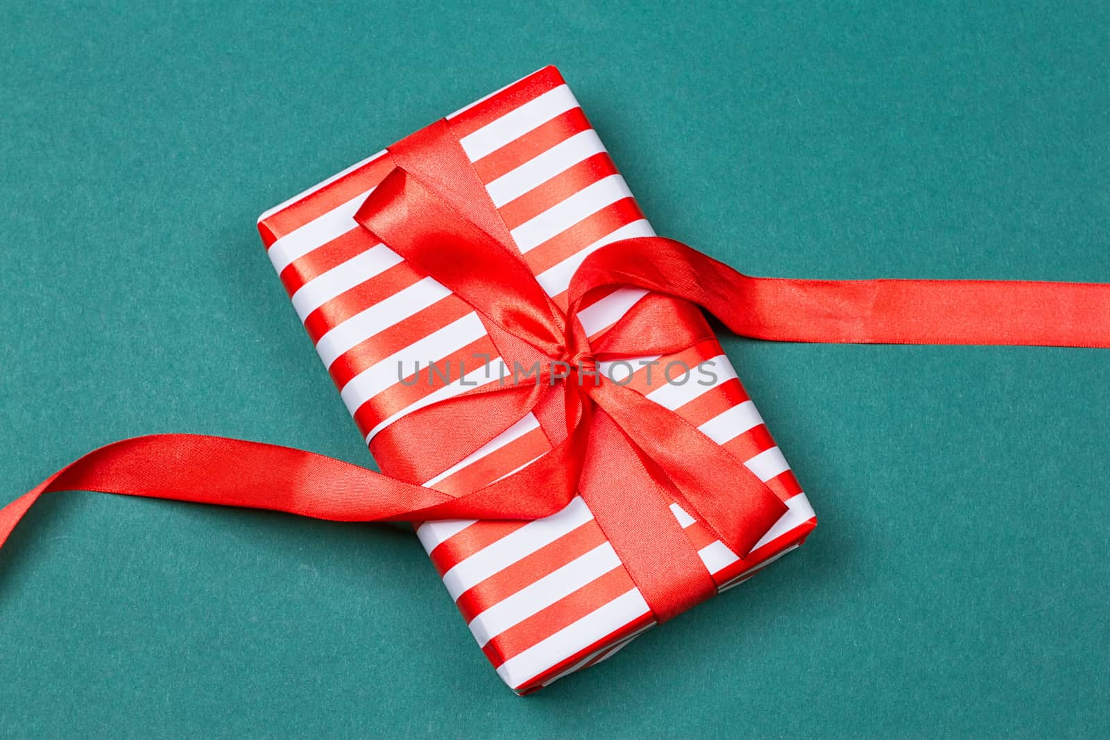 Gift box with ribbon on green background. Close up. Top view.