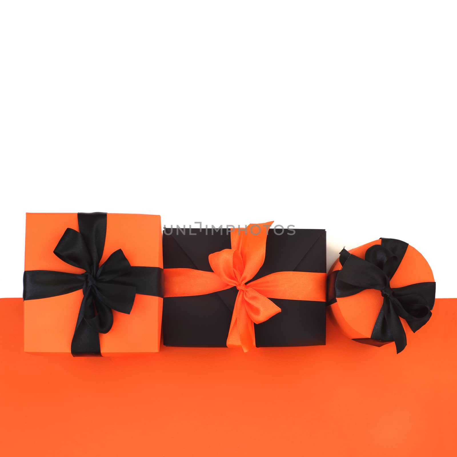 Decorated black and orange halloween gift boxes isolated on white background with reflection