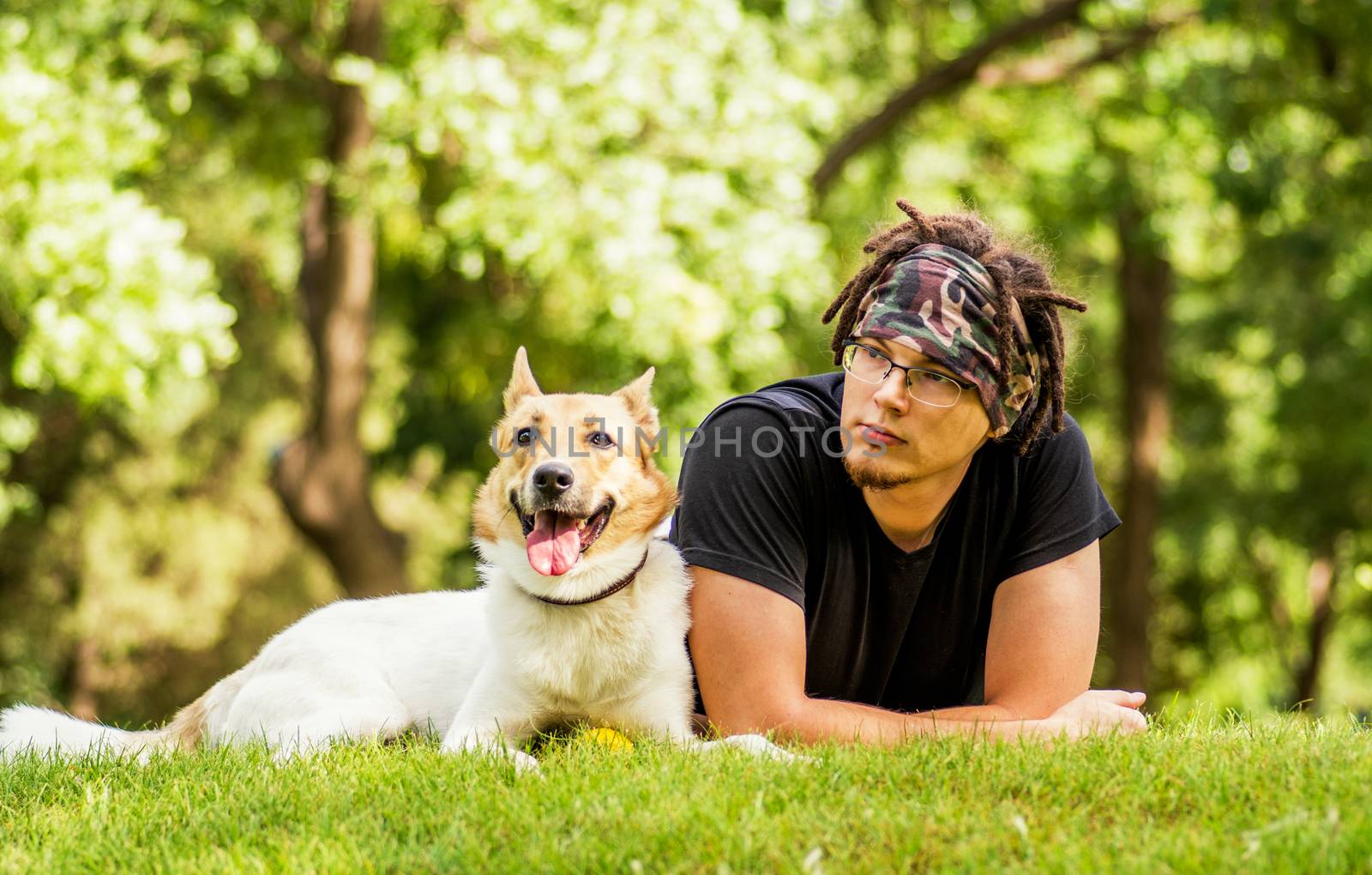caucasian guy is laying on the grass with his dog