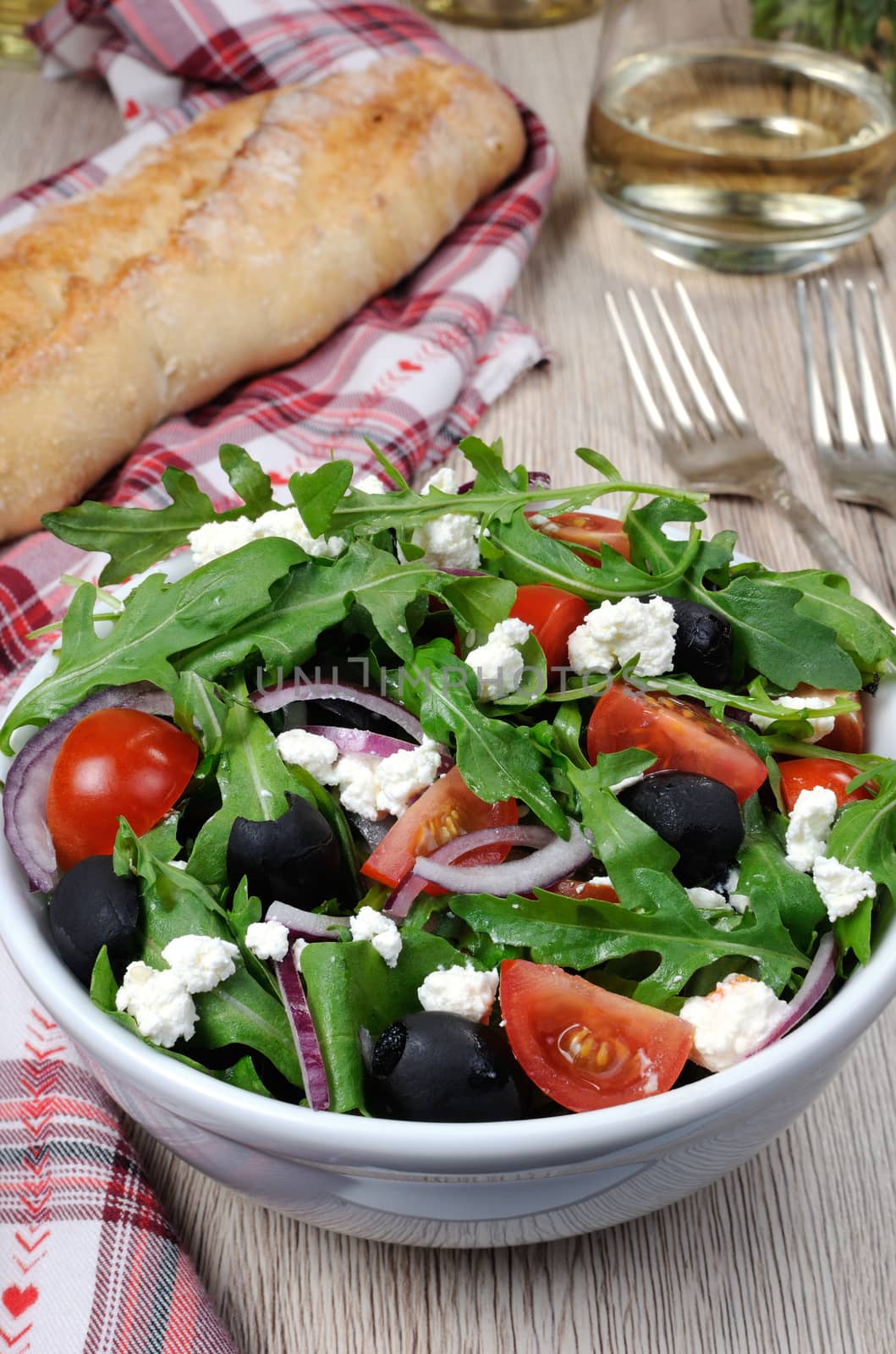 Variation of Greek salad with arugula, cherry slices, feta and olives