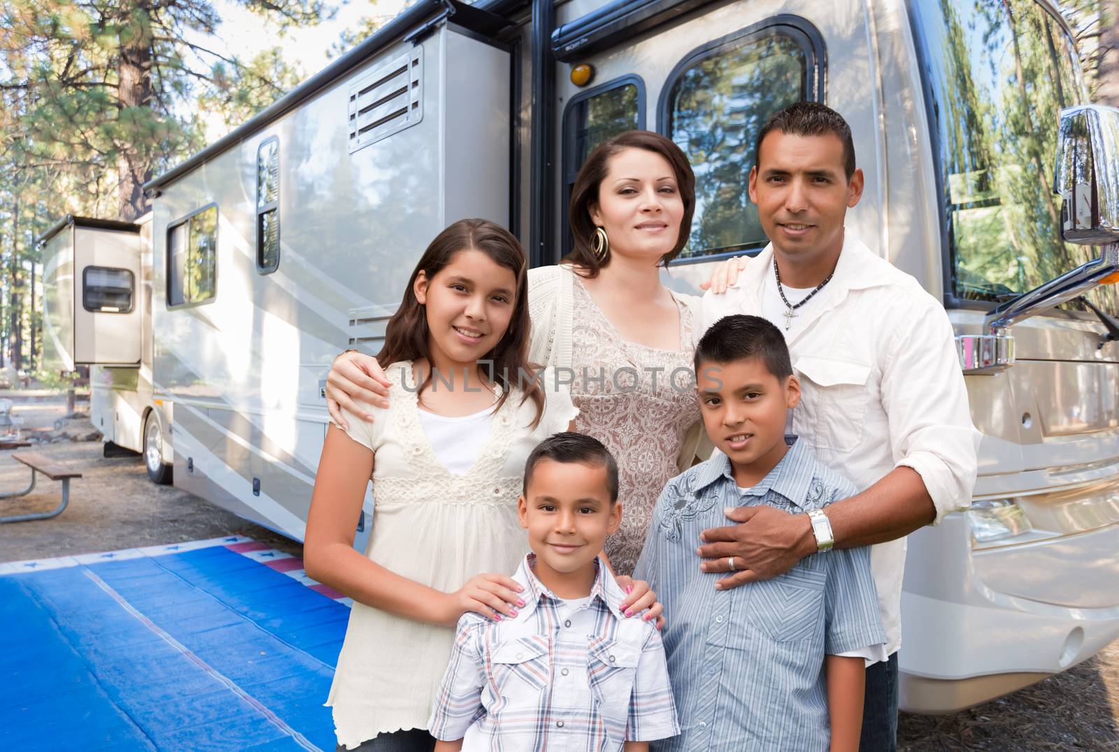 Happy Hispanic Family In Front of Their Beautiful RV At The Campground. by Feverpitched