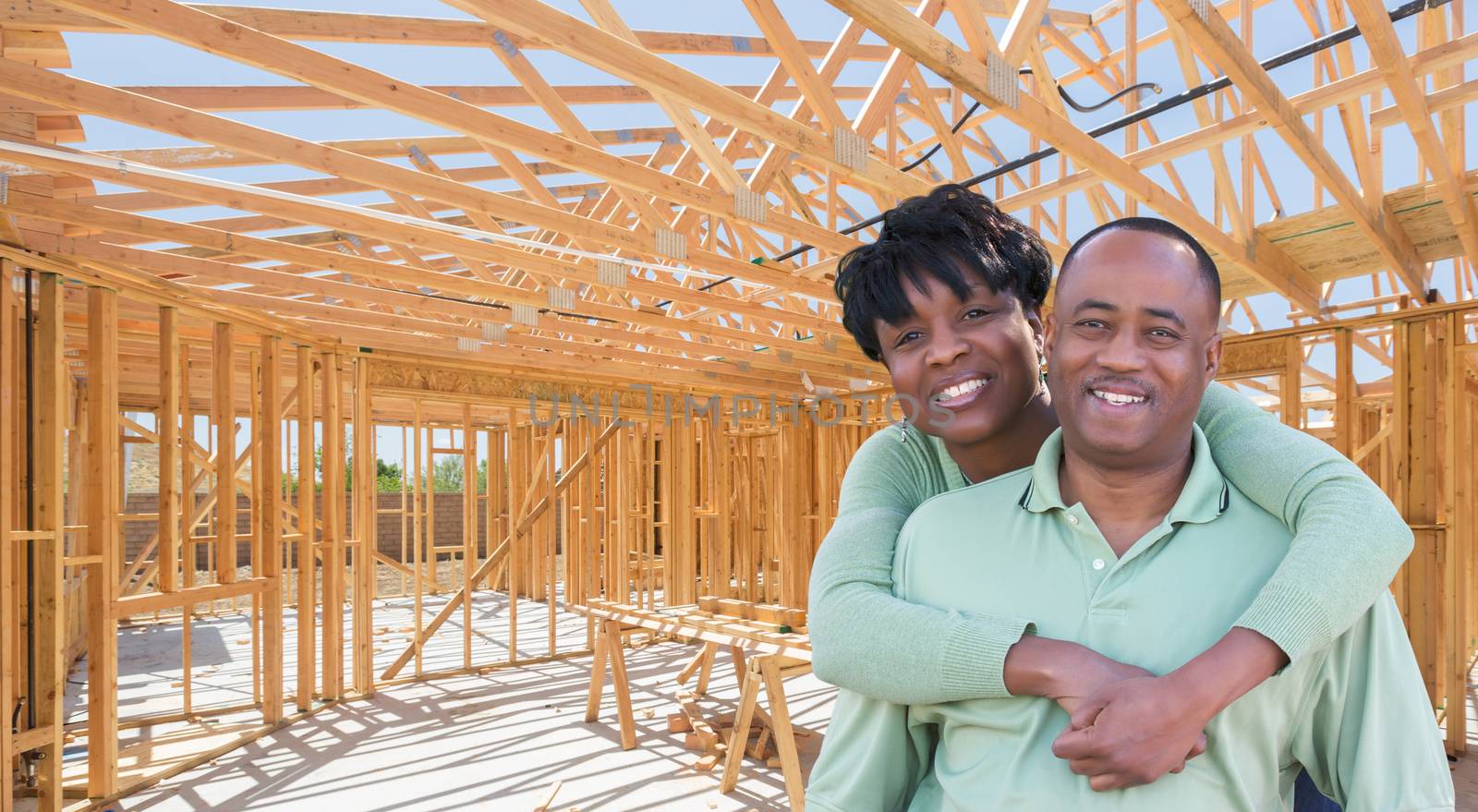 Happy African American Couple Inside Construction Framing of New House.
