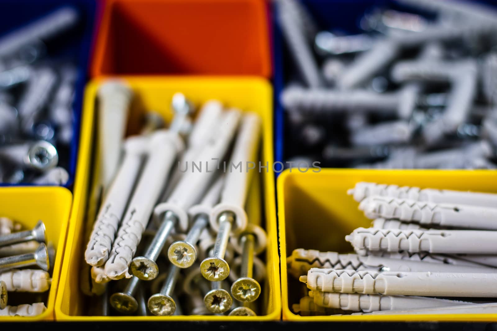 Screws segregated in plastic colored containers. Box for builder and DIY. Black background.