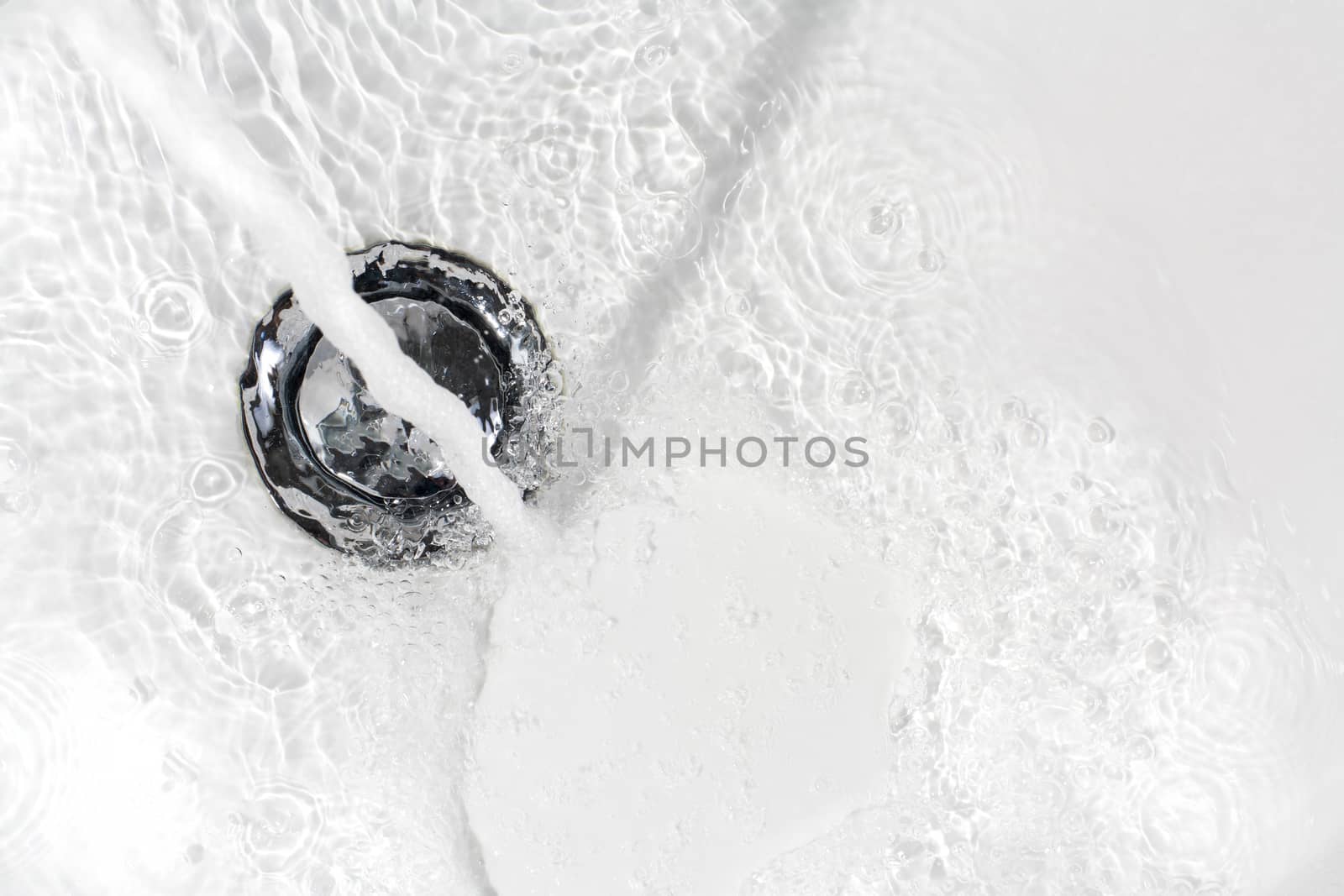 Fresh water running down the drain of a ceramic washbasin