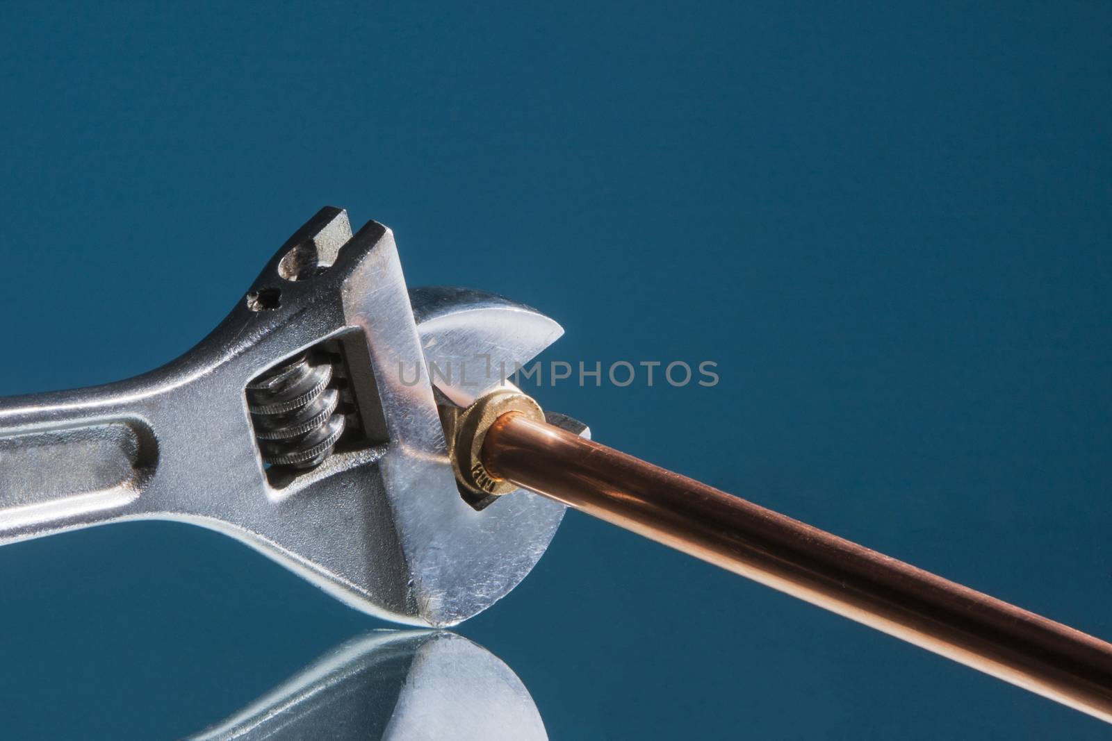 Plumber wrench for repairing a copper water pipe with a blue background