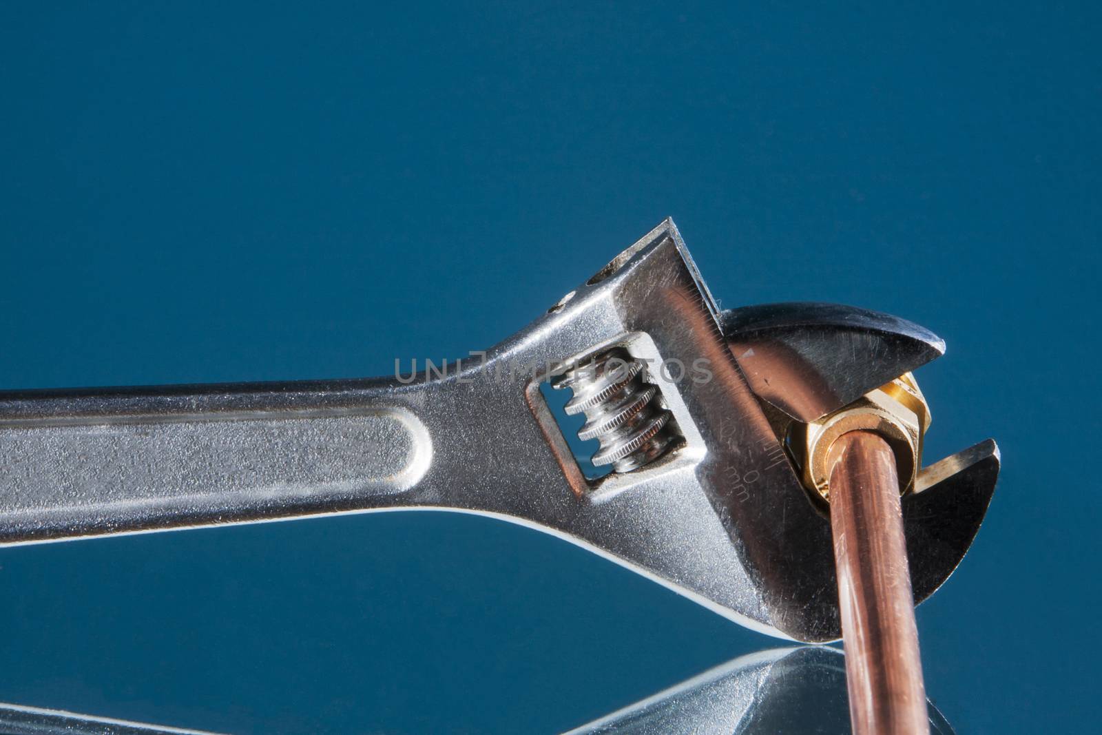 Plumber wrench for repairing a copper water pipe with a blue background