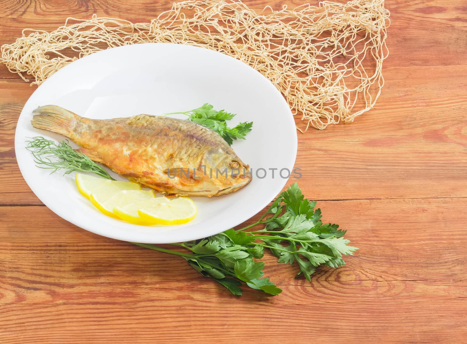 Fried crucian on white dish on an old wooden planks by anmbph