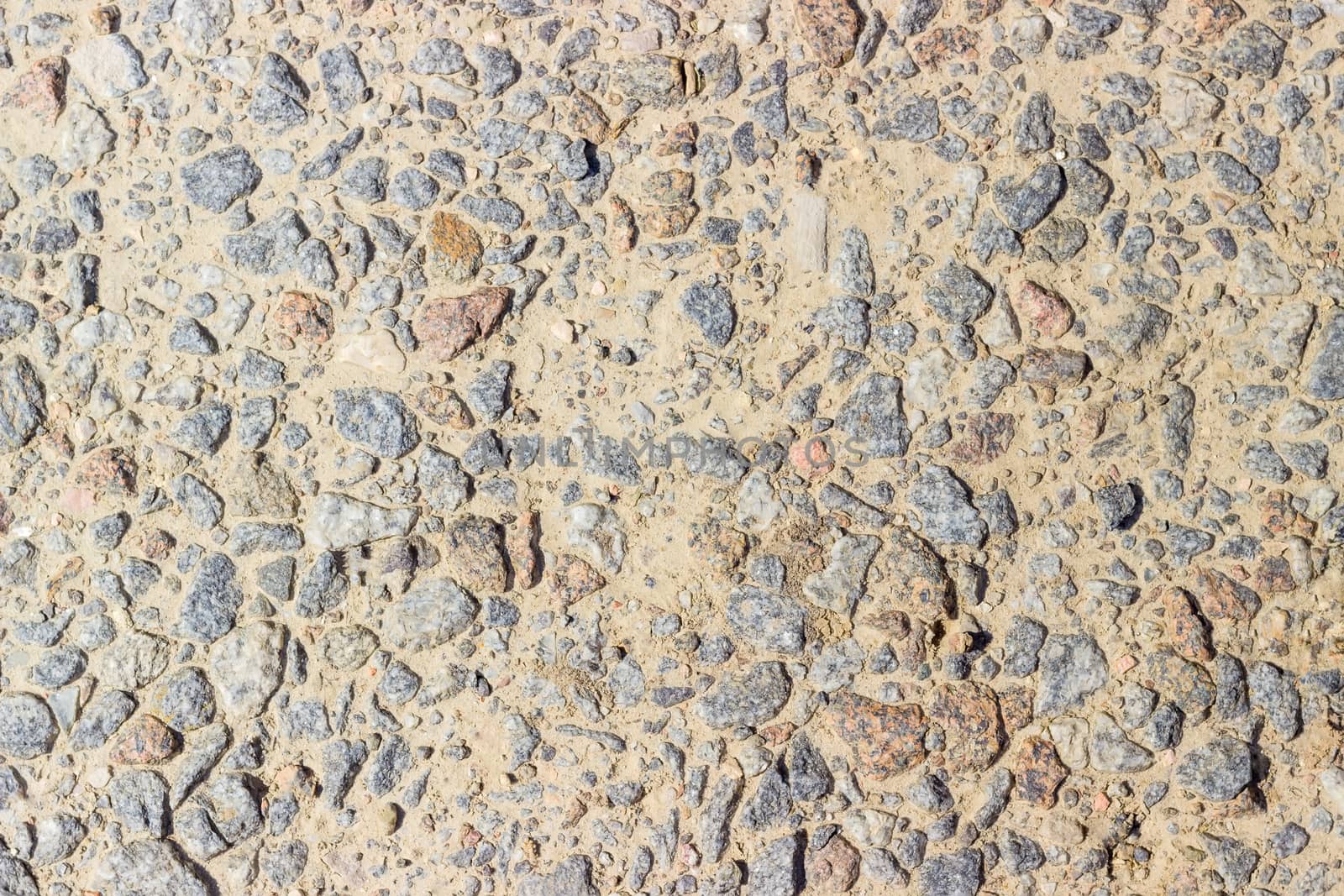 Texture of a fragment of the dirt track with inclusion of pink and gray granite gravel closeup
