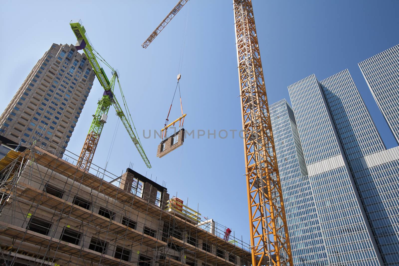 Crane lifting a wall on a construction site in Rotterdam with the Rem Koolhaas building in the background 