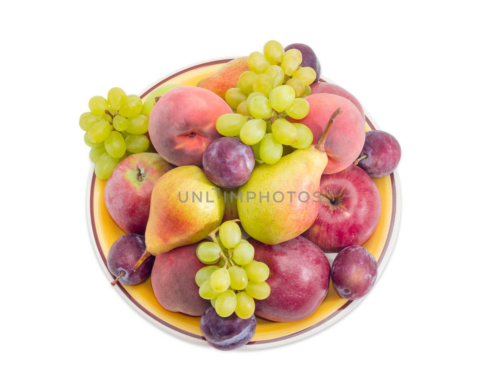 Top view of a pile of the apples, pears, plums, peaches and clusters of white grapes on a big yellow dish on a white background
