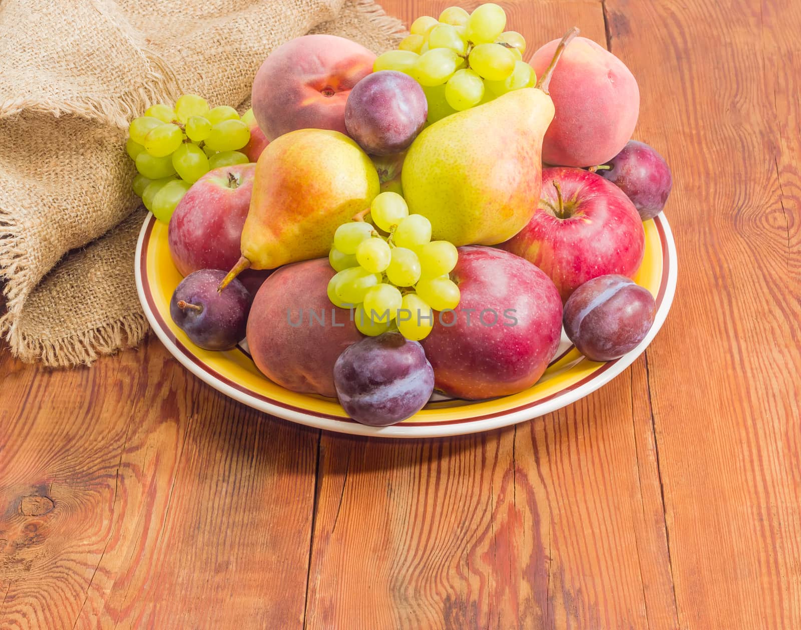 Different fruits on the big dish on a wooden surface by anmbph