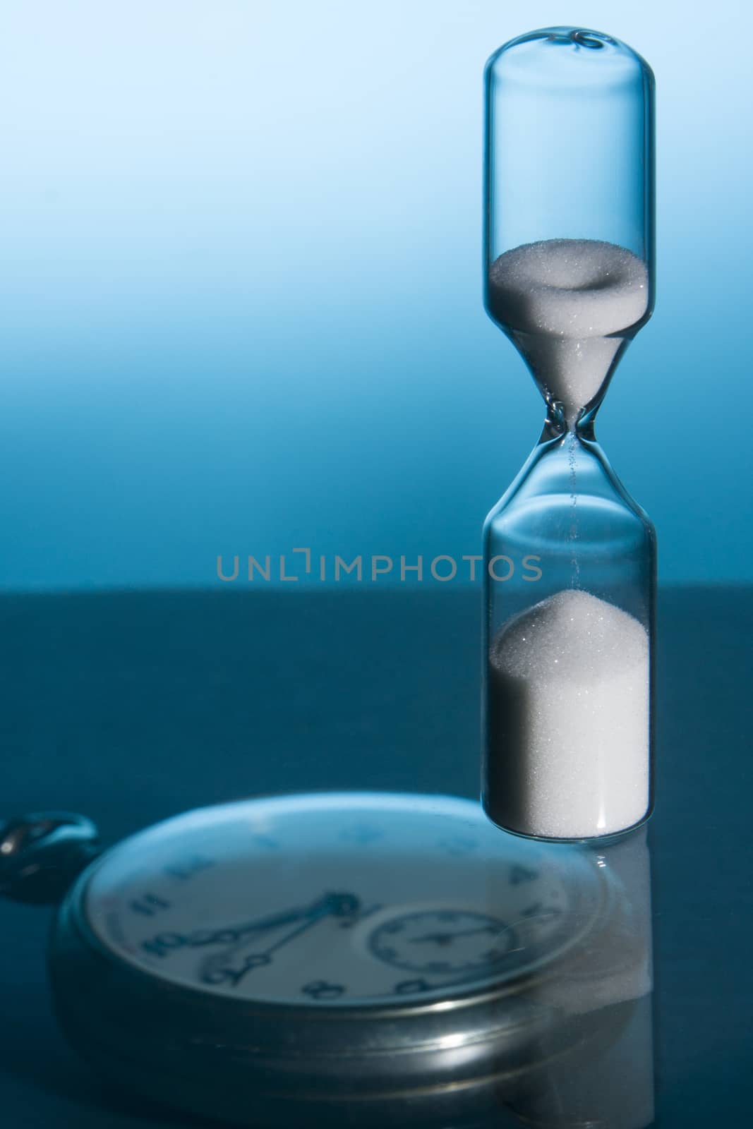 Hourglass and pocket watch with blue background