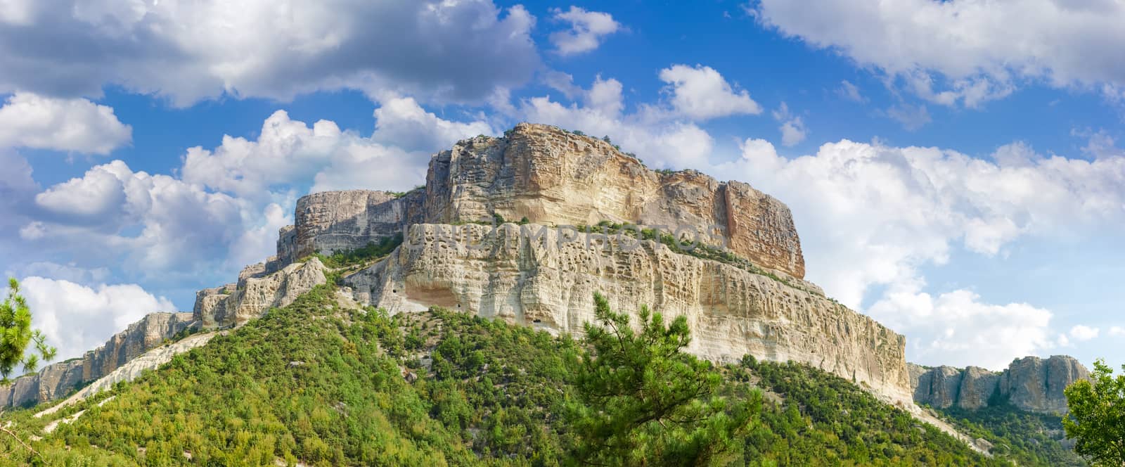 Panorama of a hillside of the limestone table hill with cliffs on a background of the sky with clouds at autumn day
