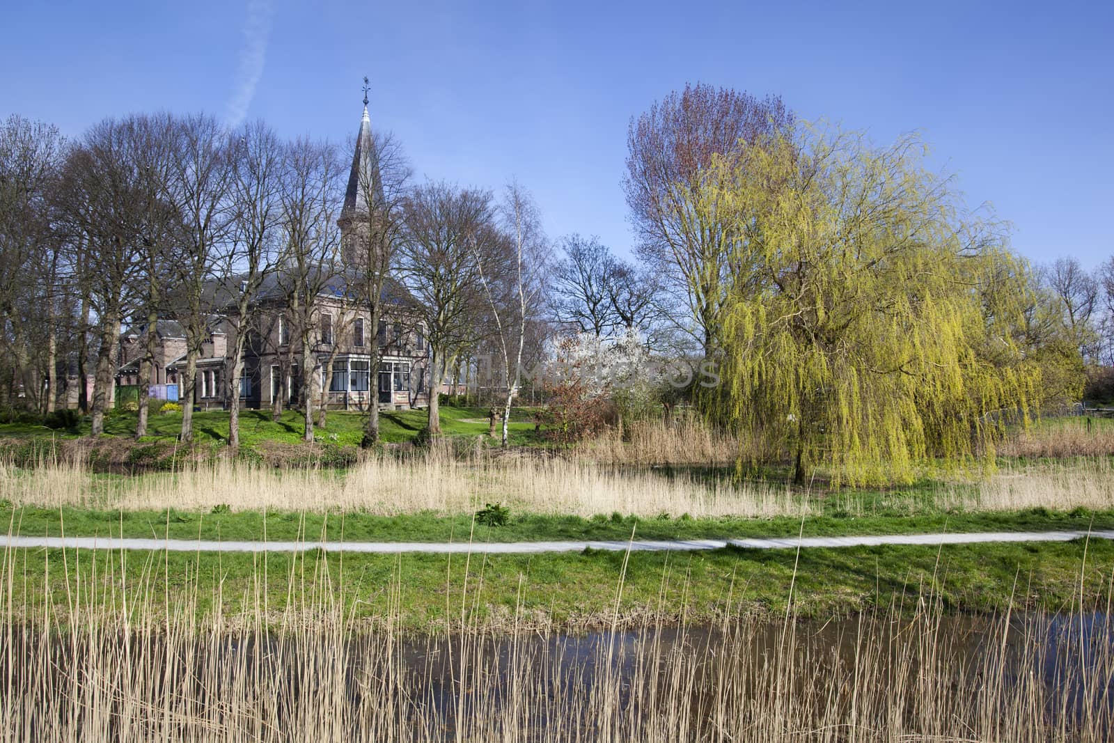 Footpath with church Jacobuskerk in village Kethel in the Netherlands