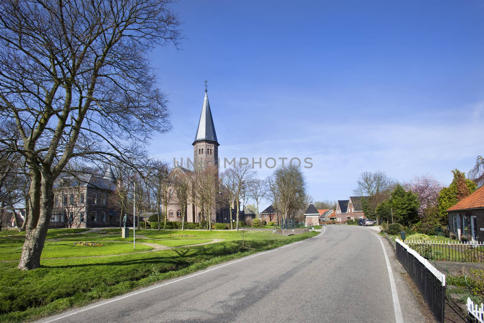 Asphalted road in village Kethel with church Jacobuskerk in the Netherlands