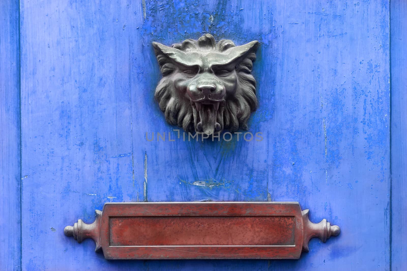 Metal doorknocker and red letter box on a blue wooden door