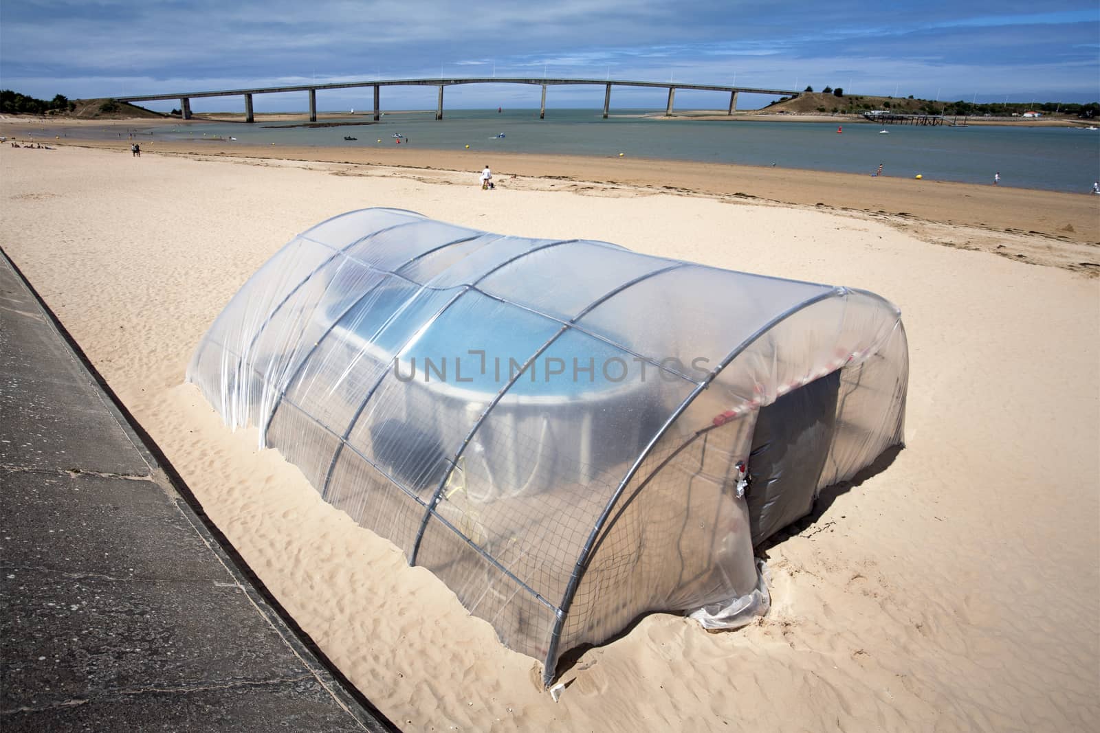 Very small indoor swimming pool on the beach of Fromentine in France. The bridge, pont of Noirmoutier, in the background