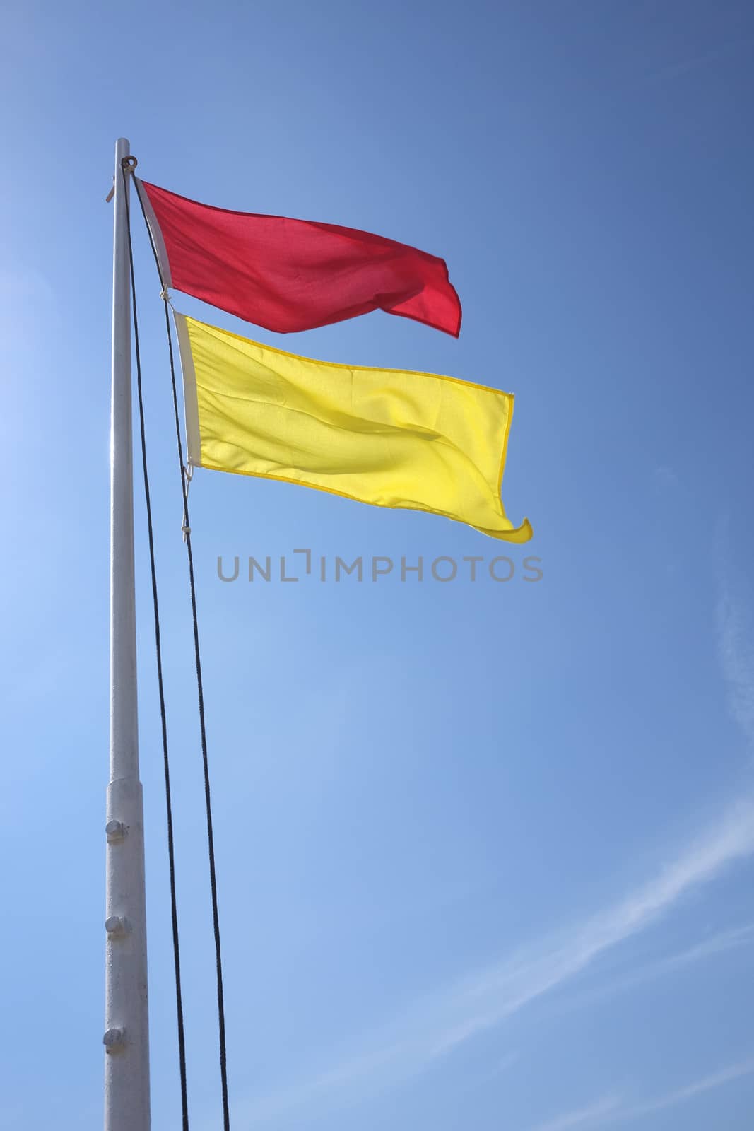 red and yellow safe bathing area flag against blue sky