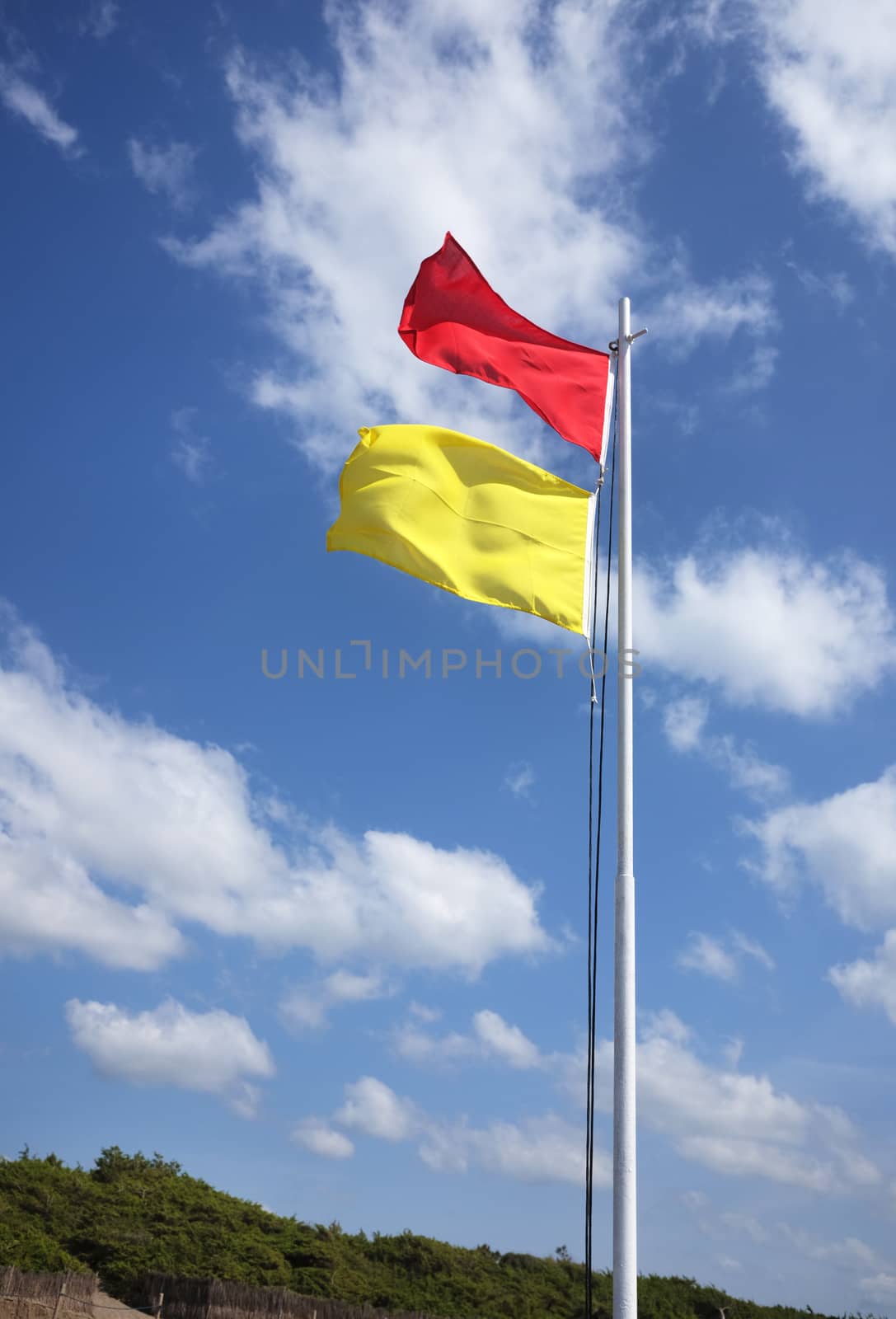 red and yellow safe bathing area flag against sky
