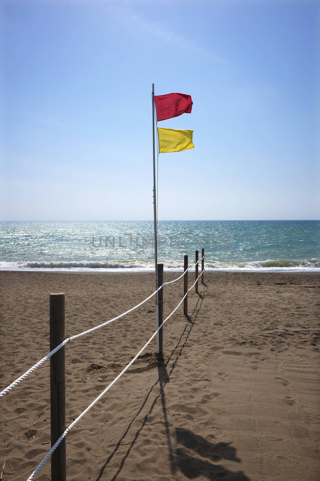 rope fence and safe bathing flag on sandy beach