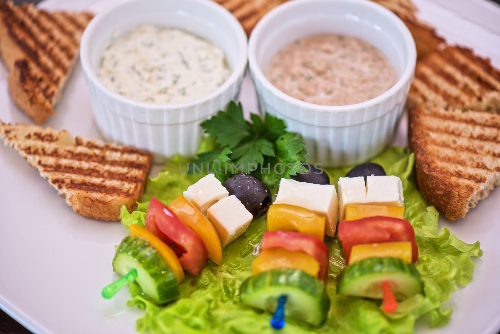 Tasty snacks: roasted toast with cheese vegetables and olive on the stick. Served with two kind of sauce