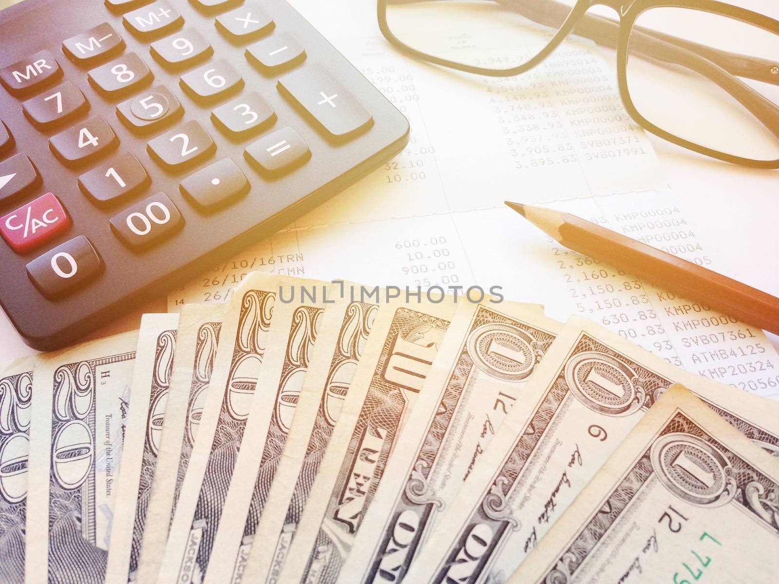 Business, finance, investment or accounting concept : Dollar money, calculator and saving account book or financial statement on office table