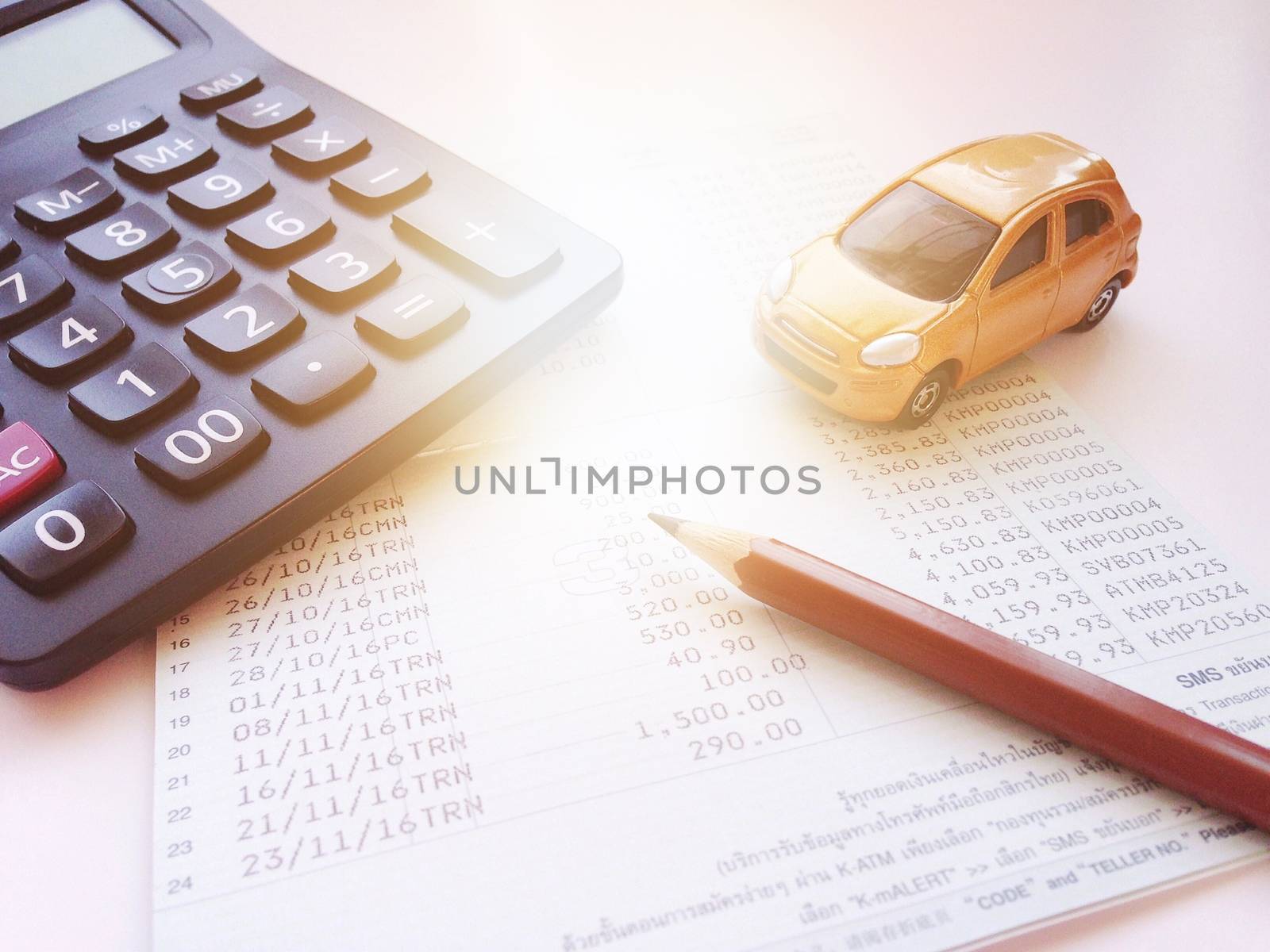 Business, finance, saving money, banking or car loan concept : Miniature car model, calculator and saving account book or financial statement on office desk table