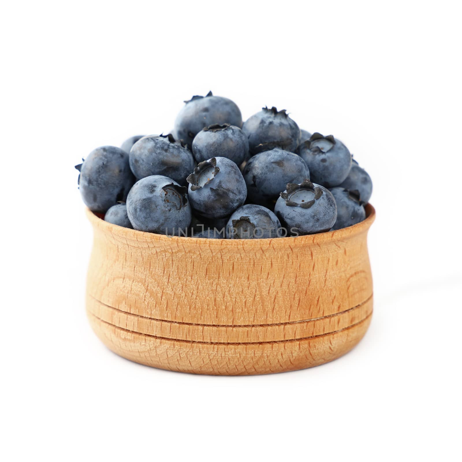 Portion of fresh blueberry berries in rustic wooden bowl isolated on white background, close up, low angle view