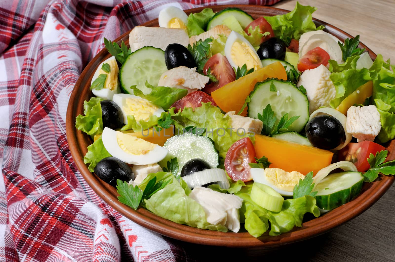 Vegetable salad with chicken and eggs, olives in lettuce leaves. Horizontal shot. Close-up.
