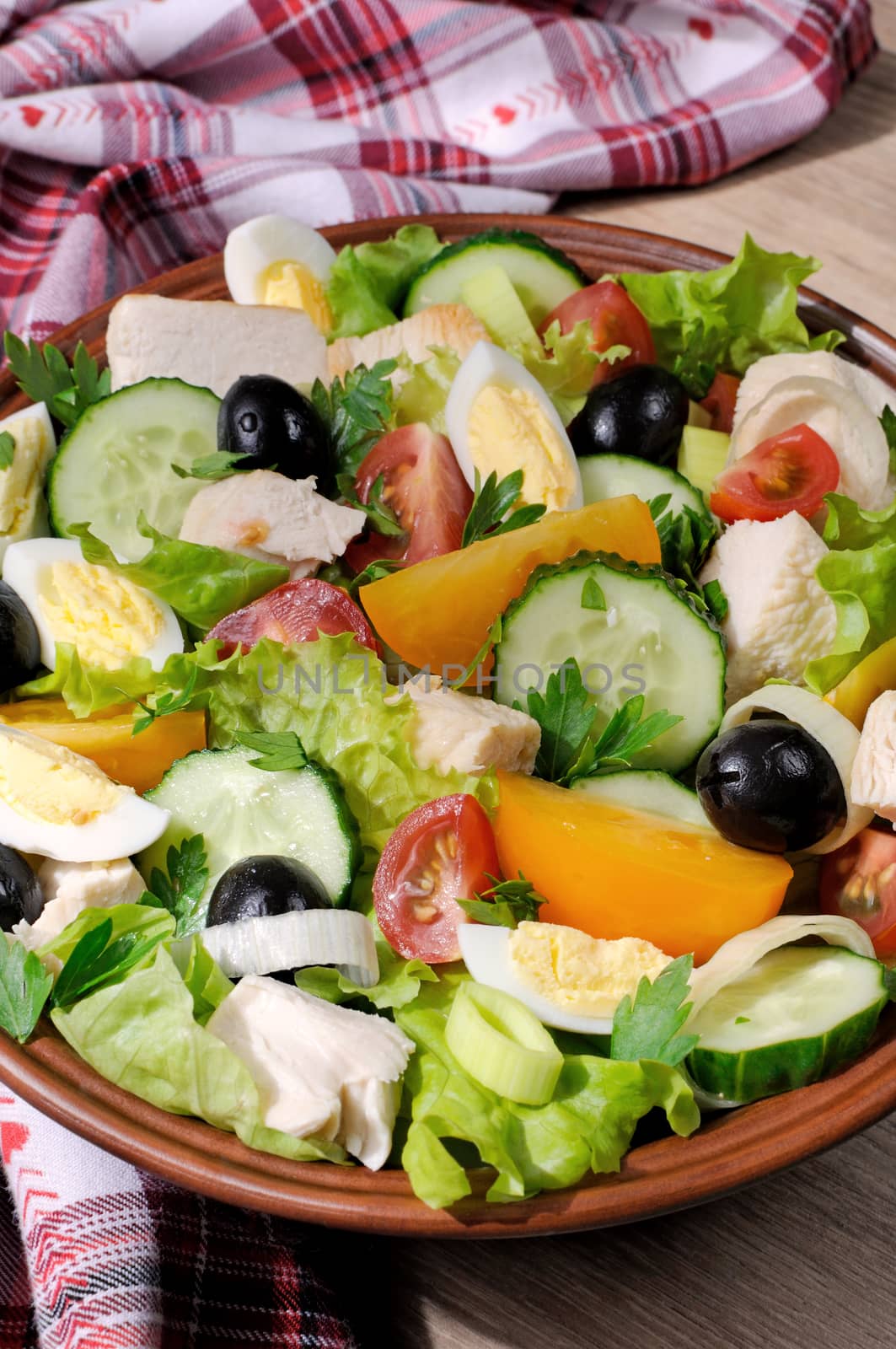 Vegetable salad with chicken and eggs, olives in lettuce leaves. Vertically  shot.
