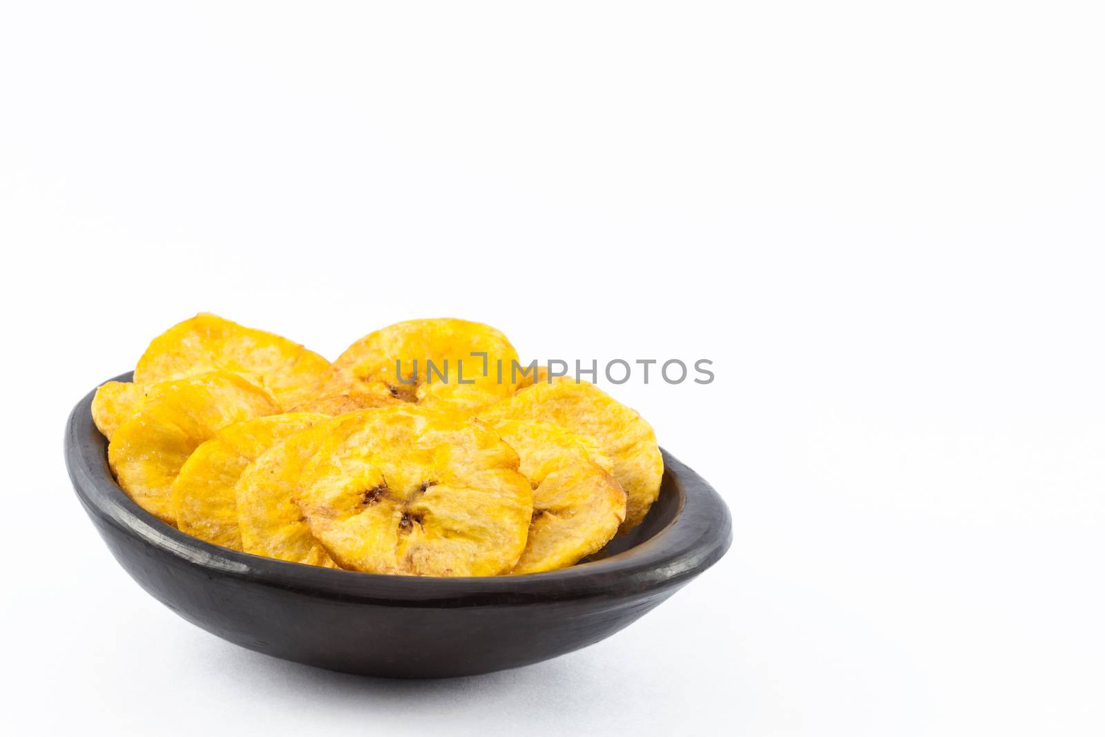 Plantain fryied coins in a traditional black clay bowl isolated on white background