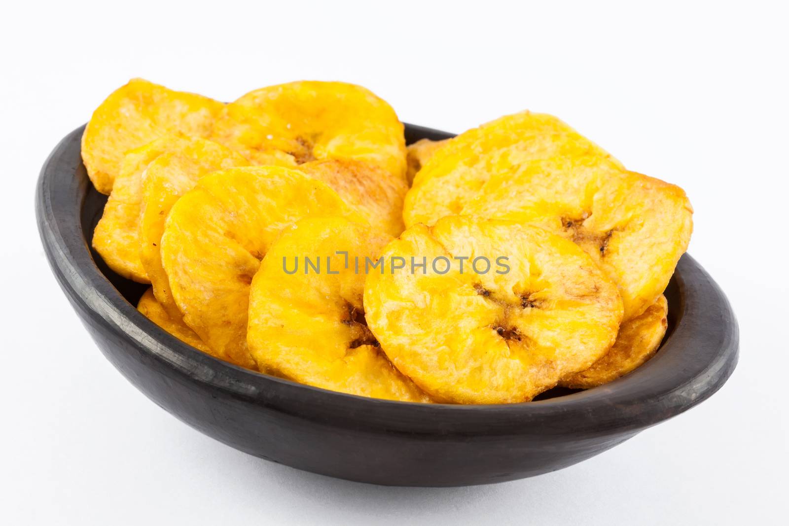 Plantain fried coins in a traditional black clay bowl isolated on white background