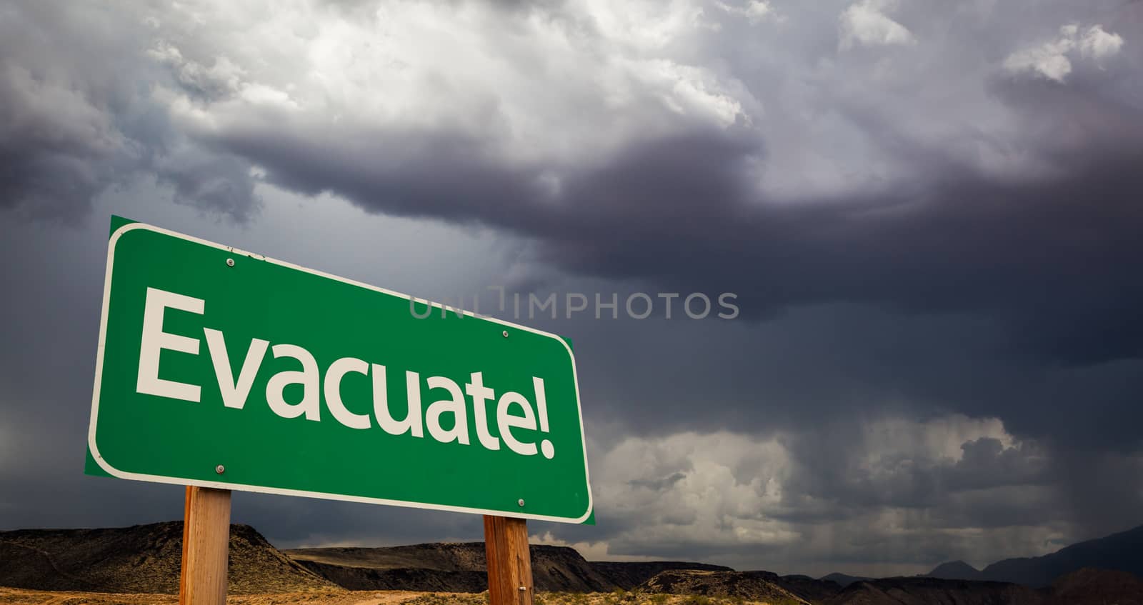 Evacuate Green Road Sign with Dramatic Clouds and Rain.