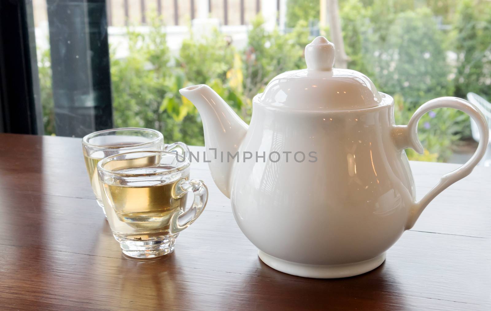 Tea pot and cups of tea on wood table with nature background