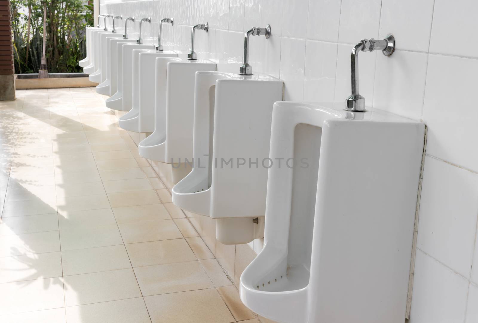 Closeup urinals white color in men's public restroom with light of sun