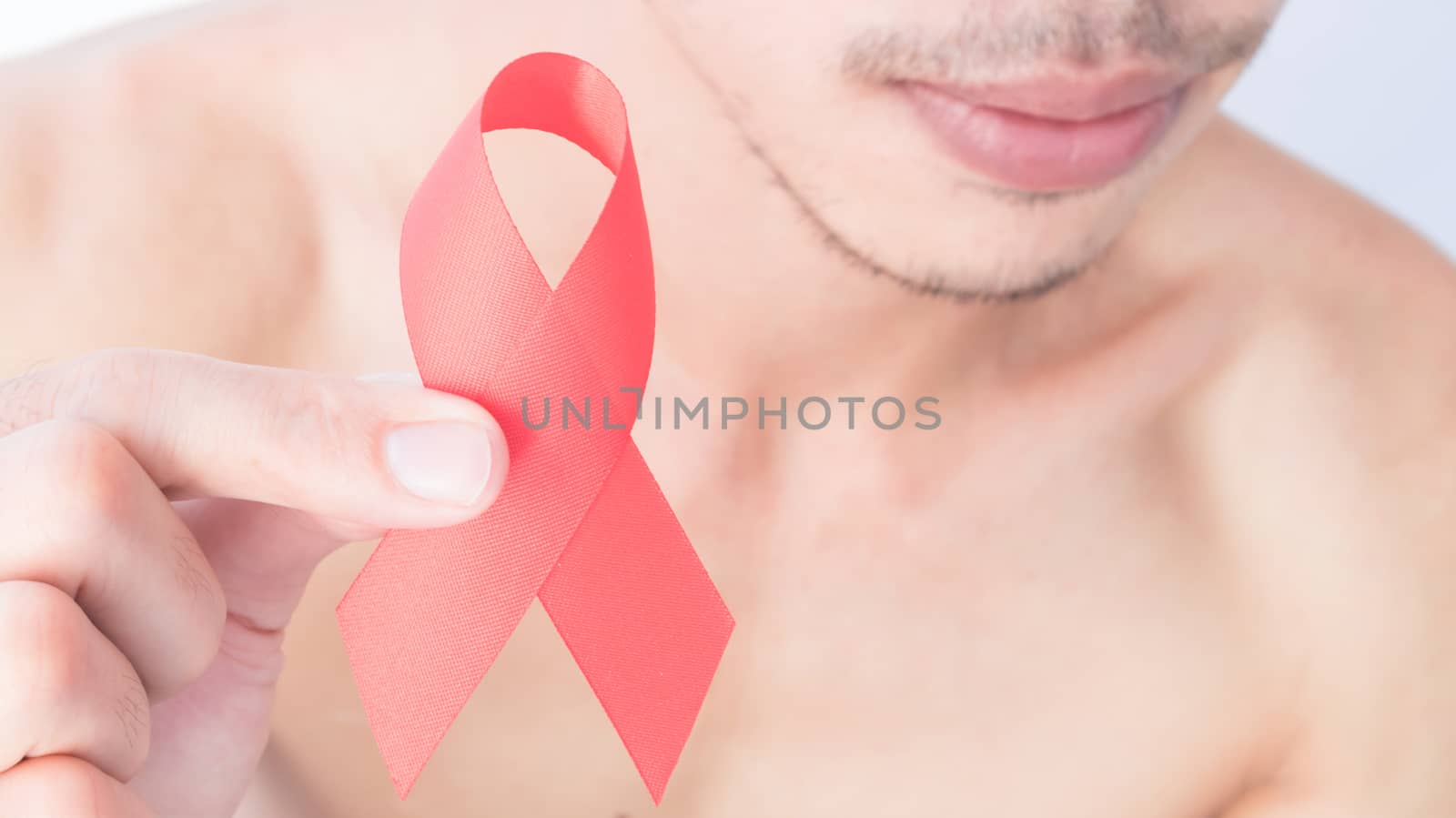 Hand hold red ribbon with blurred man background for AIDs awareness concept