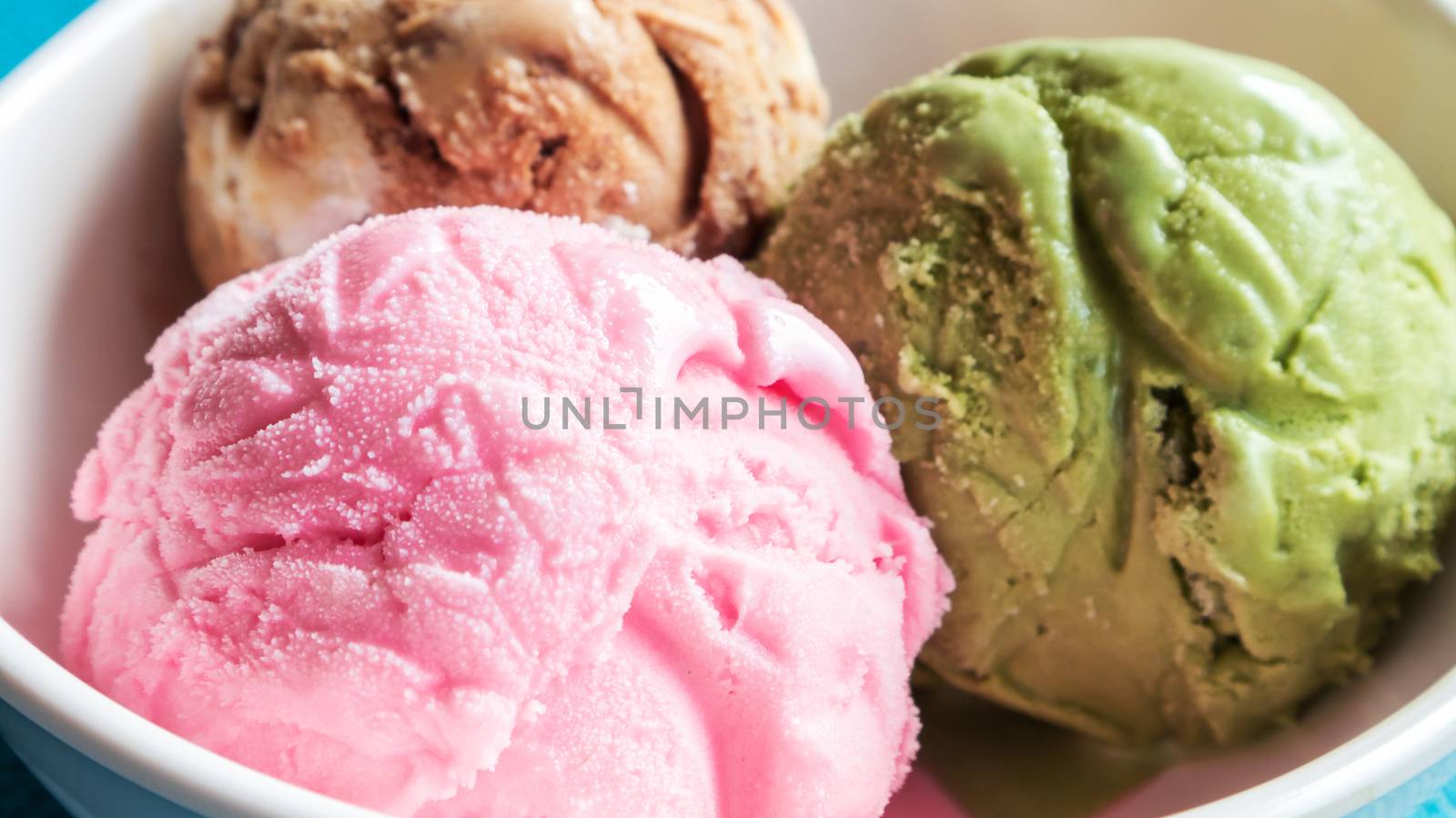 Closeup ice cream strawberry, greentea ,chocolate in the bowl on blue background