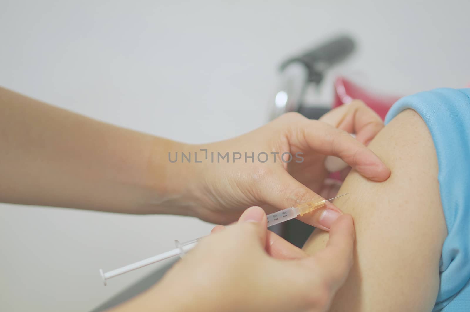 Nurse holding hypodermic syringe inject vaccine with patient on wheelchair by eaglesky