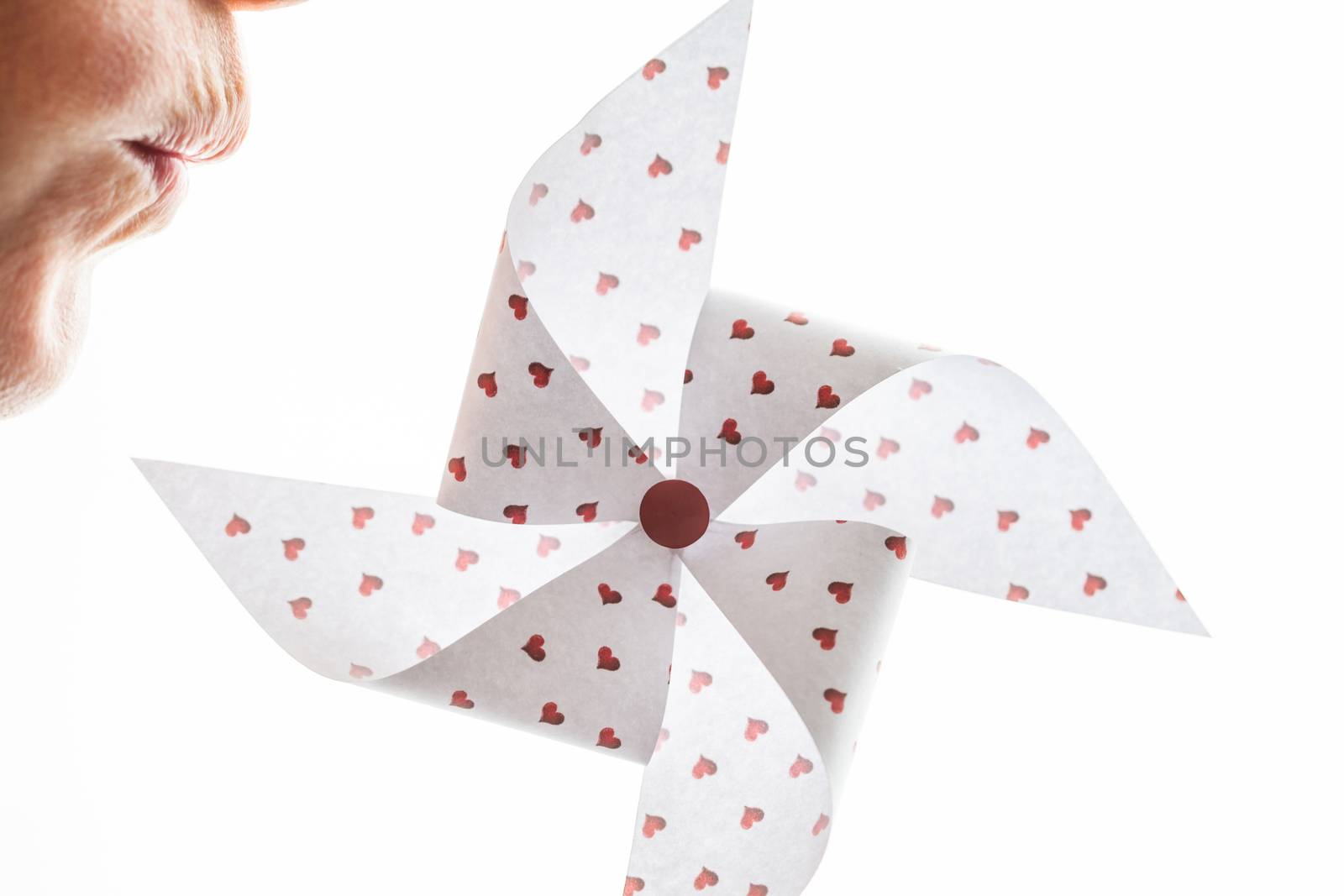 Woman blowing a hearts paper pinwheel isolated on white background