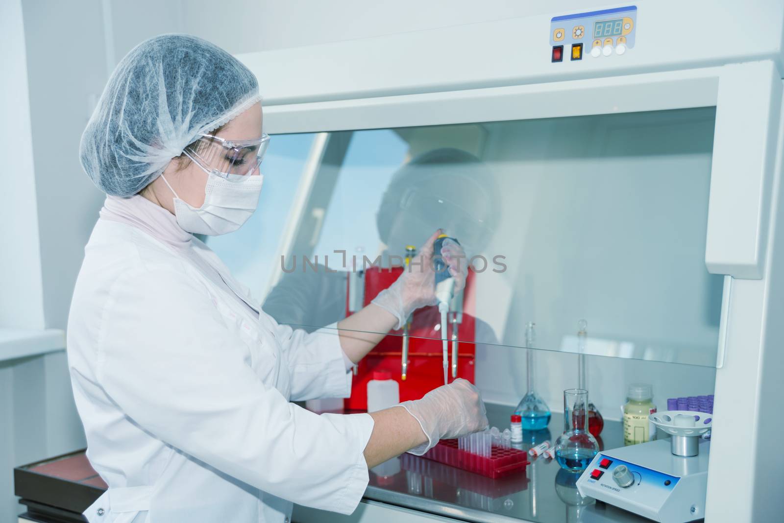 Woman scientist in a white protective clothing conducts research in a lab