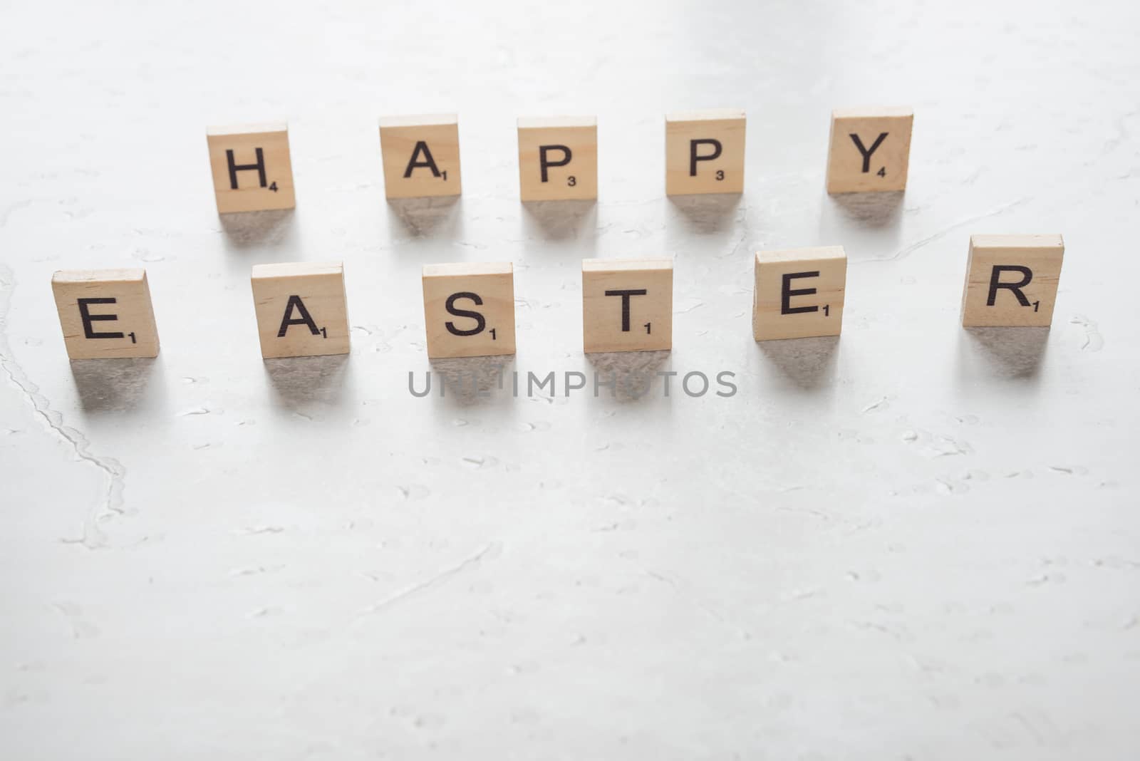 Easter concept: the inscription "Happy Easter", consisting of wooden game pieces with letters on a stone background