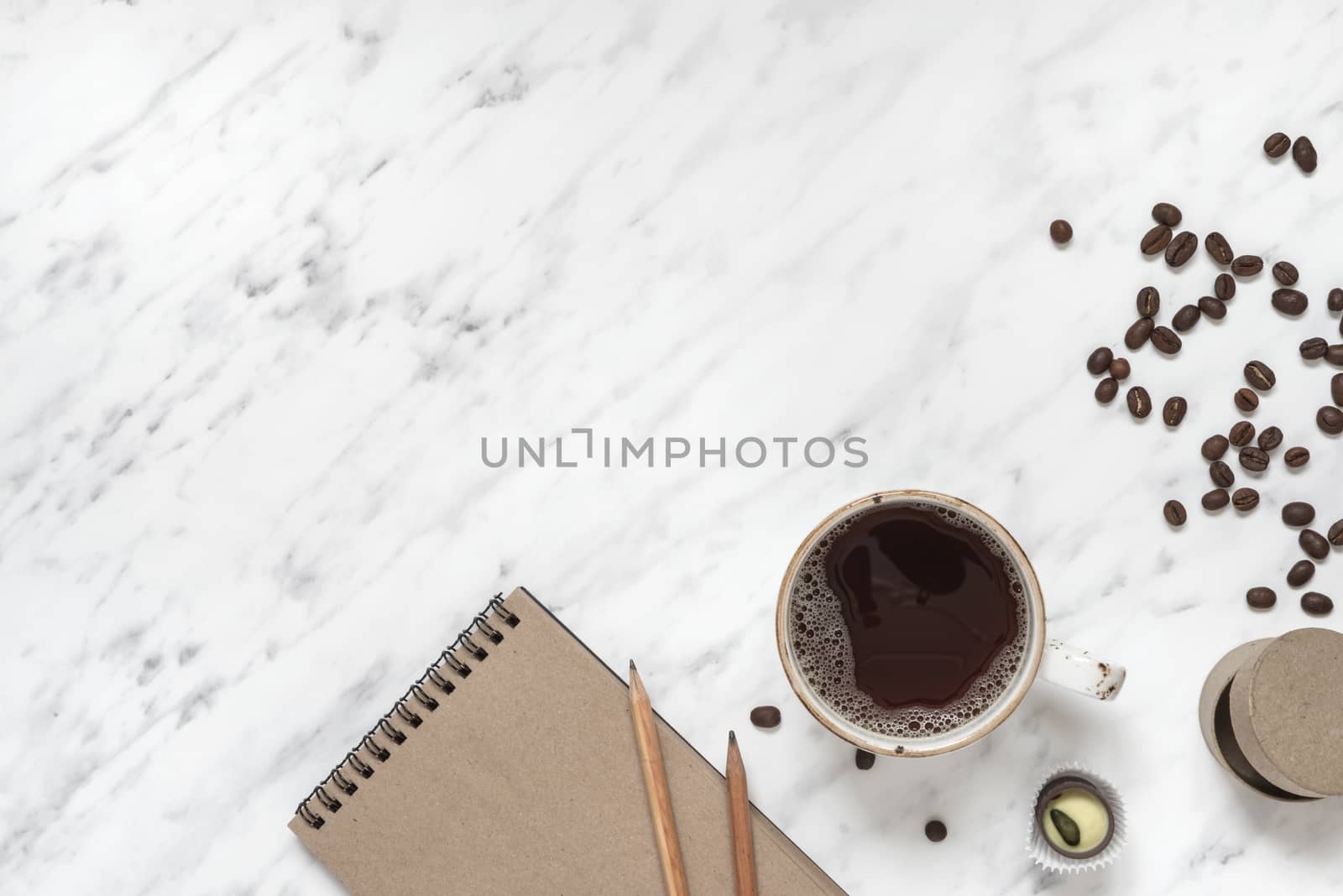 Morning composition with a cup of black coffee and a notebook on a marble surface with space for text, top view