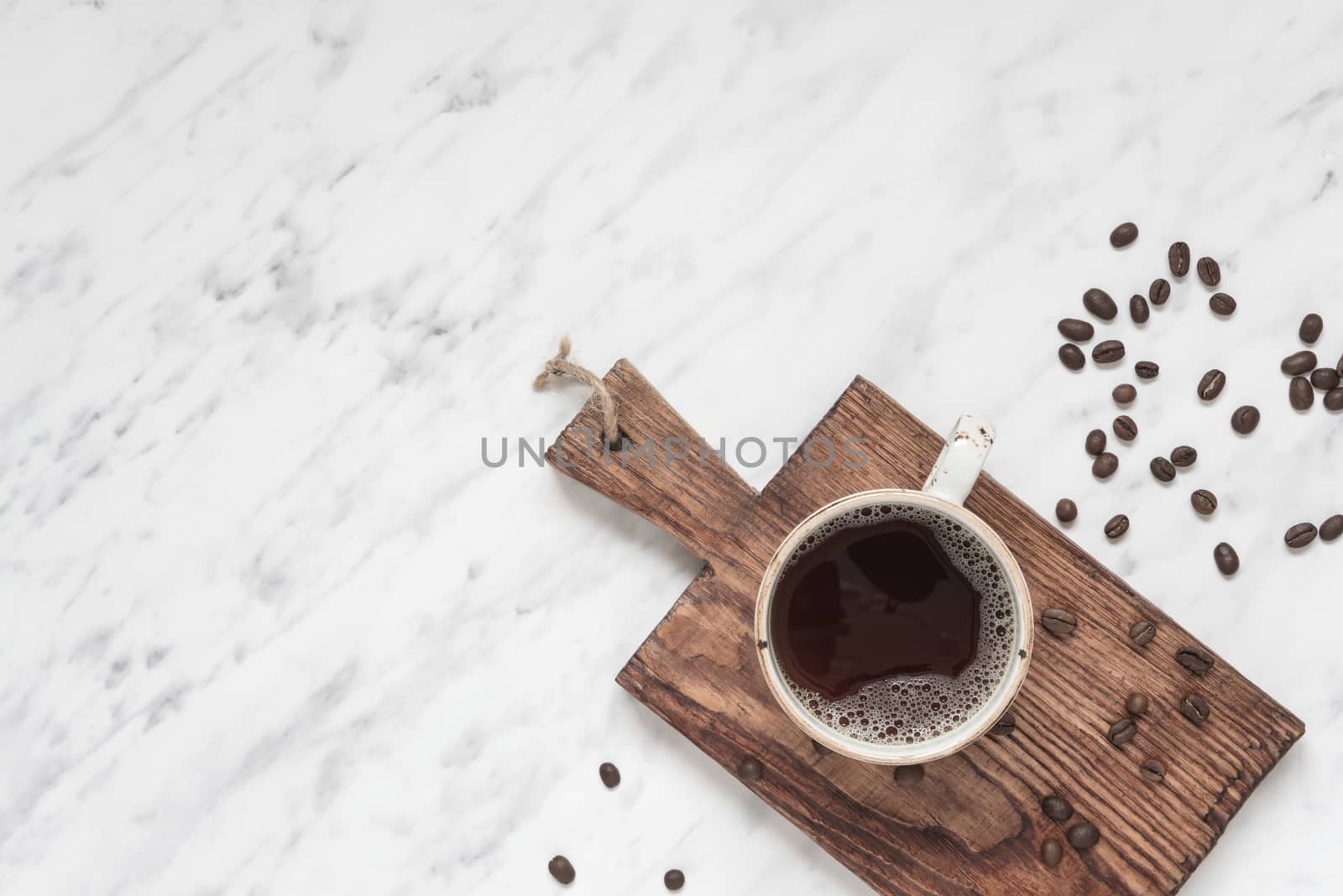 Morning composition with a cup of black coffee and coffee beans on a marble surface with space for text, top view