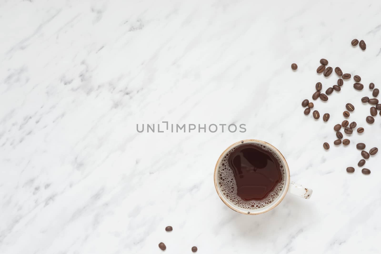 Morning composition with a cup of black coffee and coffee beans on a marble surface with space for text, top view